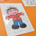 Desenho de um menino moreno, de braços abertos com camisola vermelha, calças azuis e sapatos pretos.